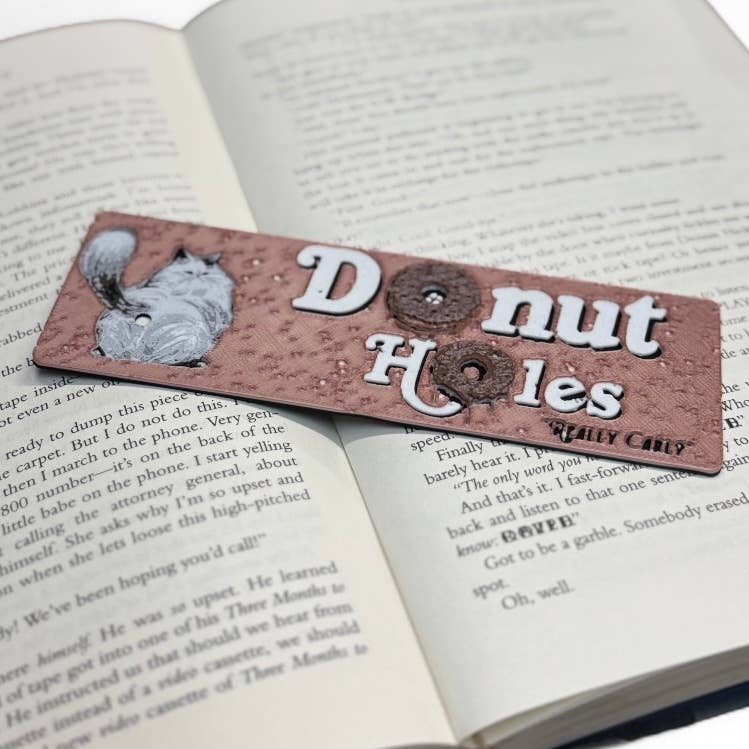 Bookmark with 'Donut Holes' text and donut graphic on an open book