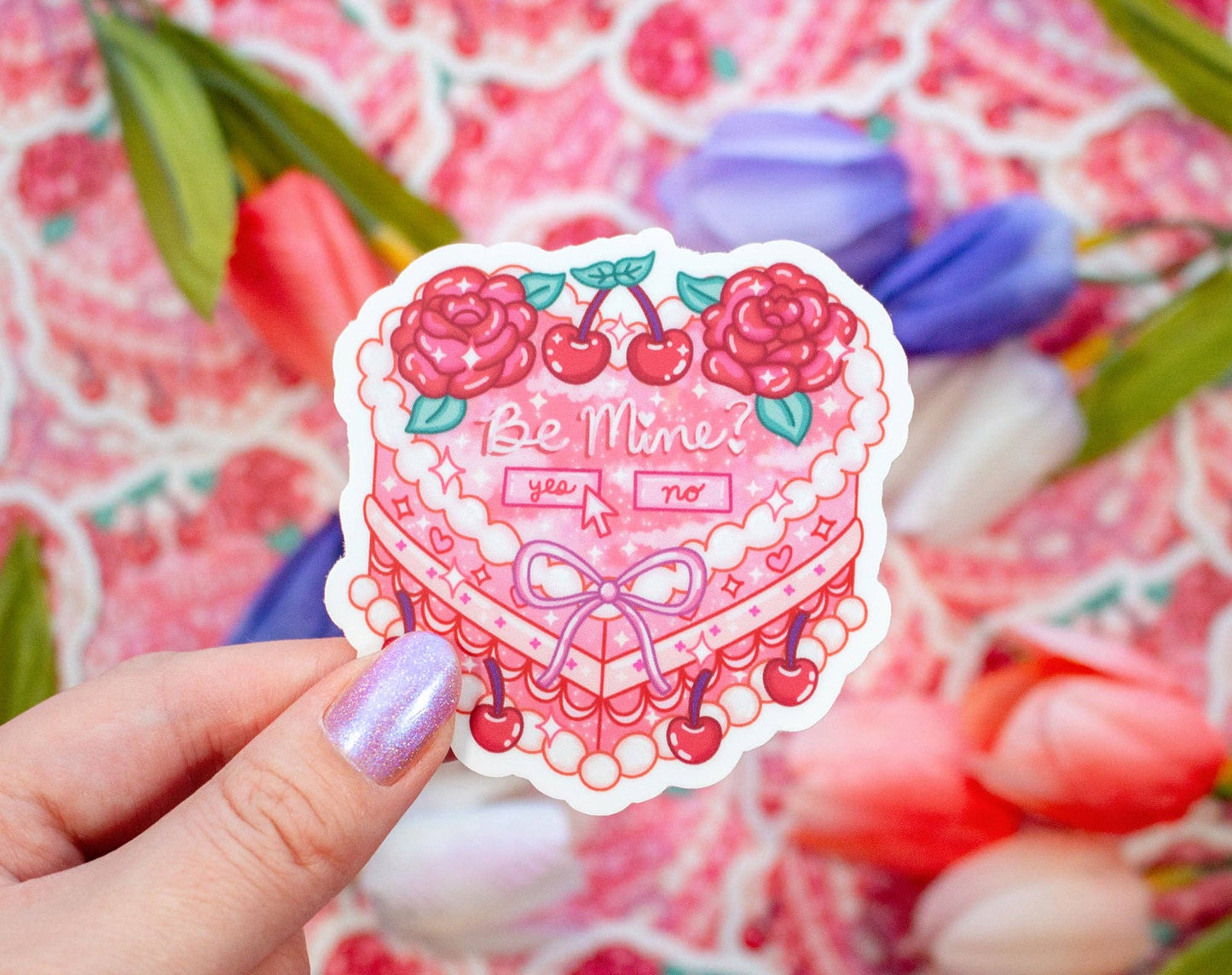 Sticker with heart design and 'Be Mine' text held by a hand against a colorful background.