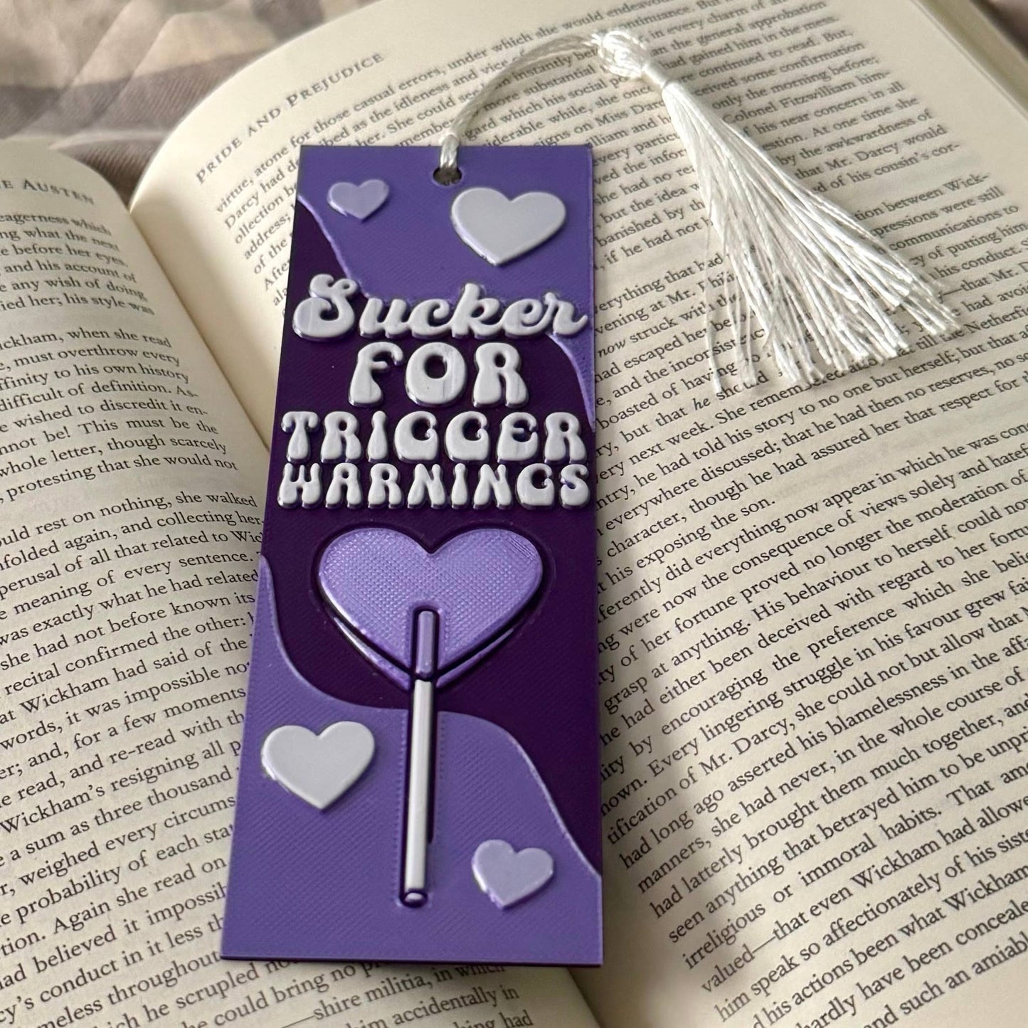 Bookmark with 'Sucker For Trigger Warnings' text on a book page
