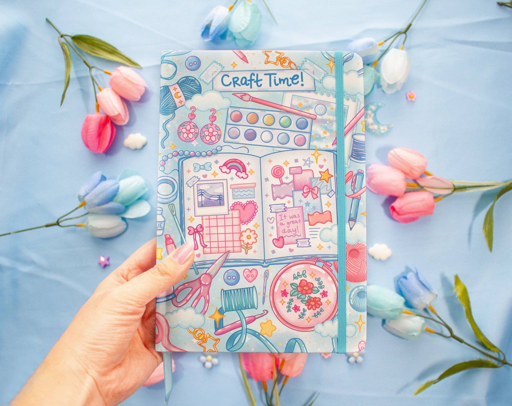 Decorative sticker book titled 'Craft Time!' held by a hand with flowers on a blue background