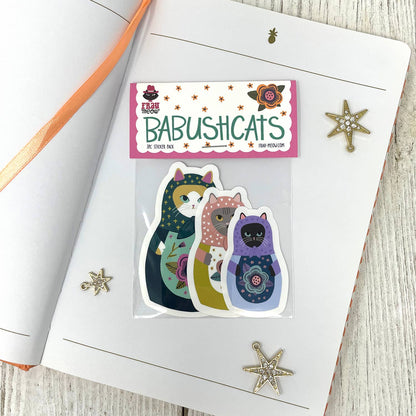 Packaged stickers with 'Babushicats' branding on a wooden surface
