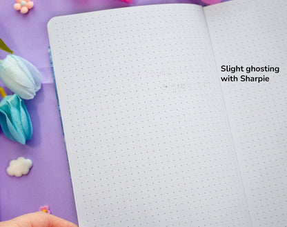 Open notebook with dotted pages and text on a purple background 