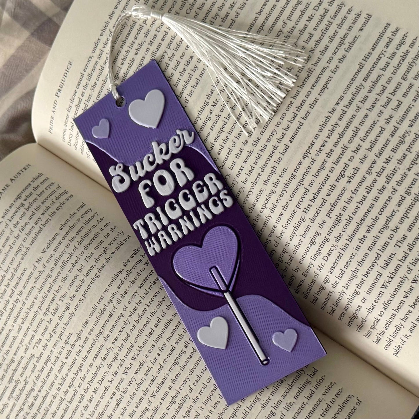 Purple bookmark with text and heart designs on an open book