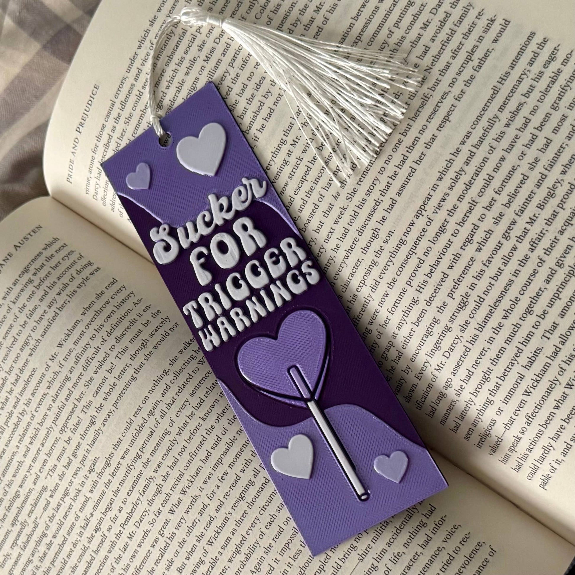 Purple bookmark with text and heart designs on an open book