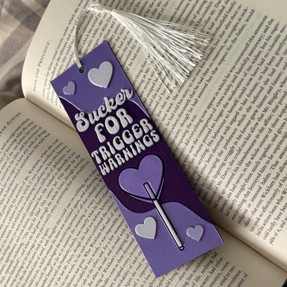 Purple bookmark with text and heart designs on an open book