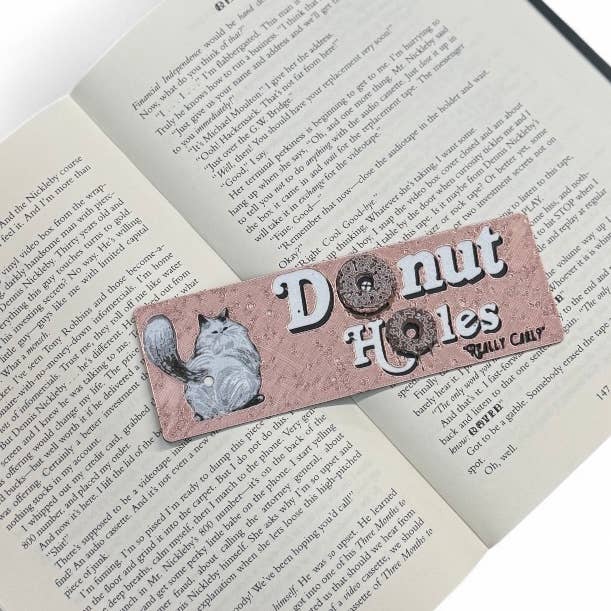 Bookmark with a cat illustration and text 'Donut Holes Really Cally' on an open book.