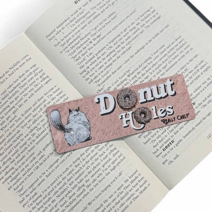 Bookmark with a cat illustration and text 'Donut Holes Really Cally' on an open book.