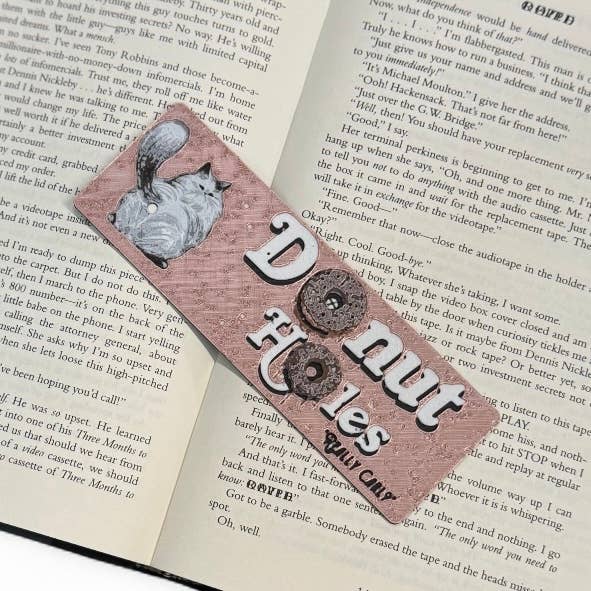 Bookmark with a cat illustration and text on an open book