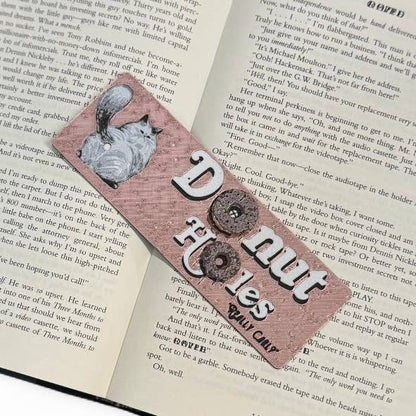 Bookmark with a cat illustration and text on an open book