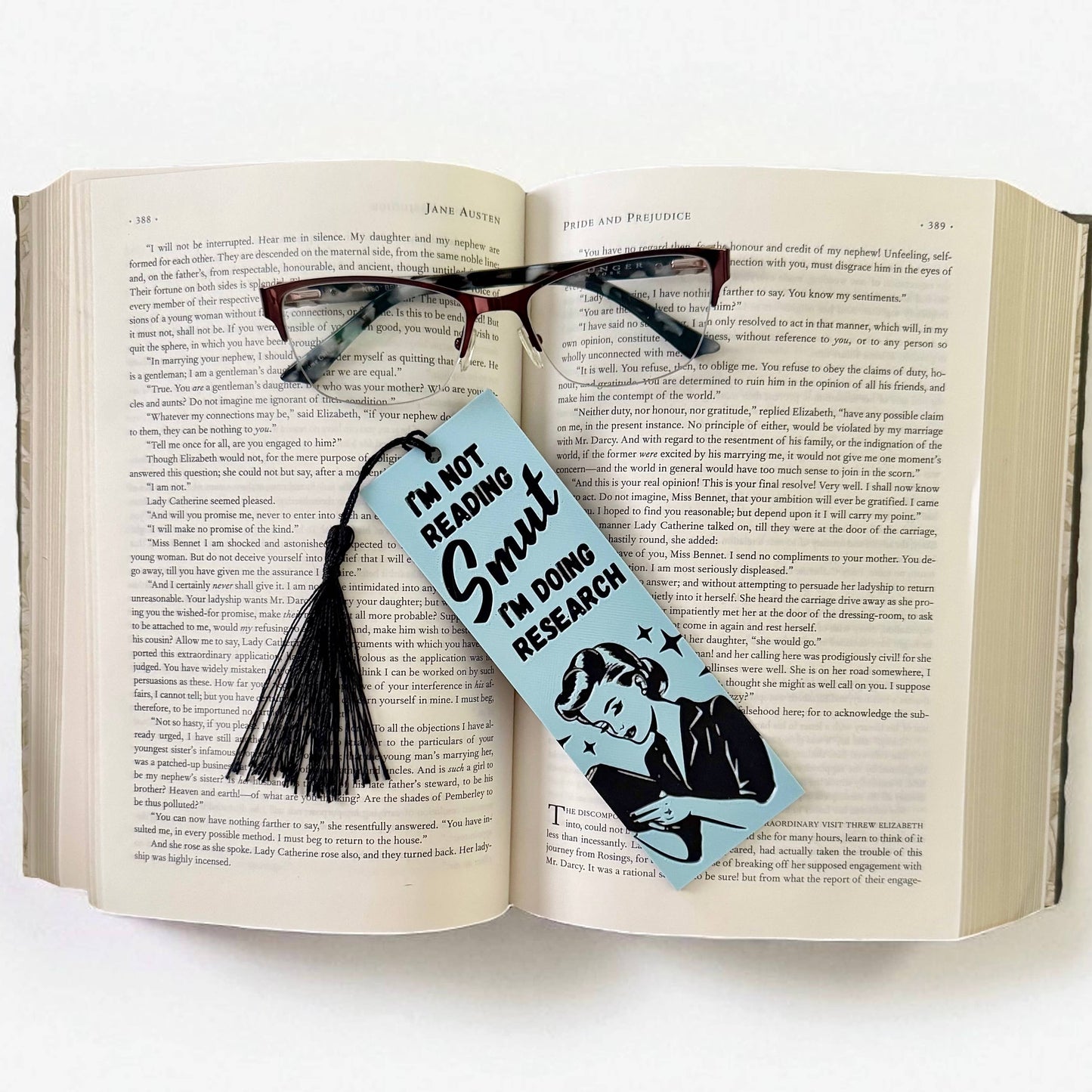 Open book with a bookmark and glasses on a white background