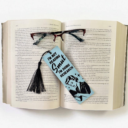 Open book with a bookmark and glasses on a white background
