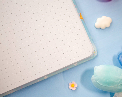 Notebook with a dotted page on a blue surface with decorative items