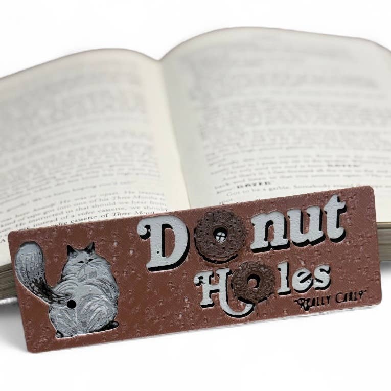Decorative sign with 'Donut Holes' text and a cat illustration on an open book.